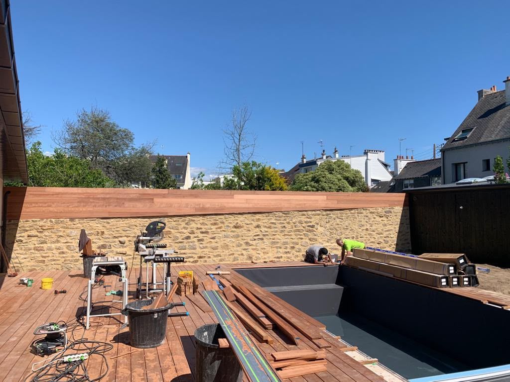 Patio de jardin en cours d’aménagement, avec du bois empilé, des outils