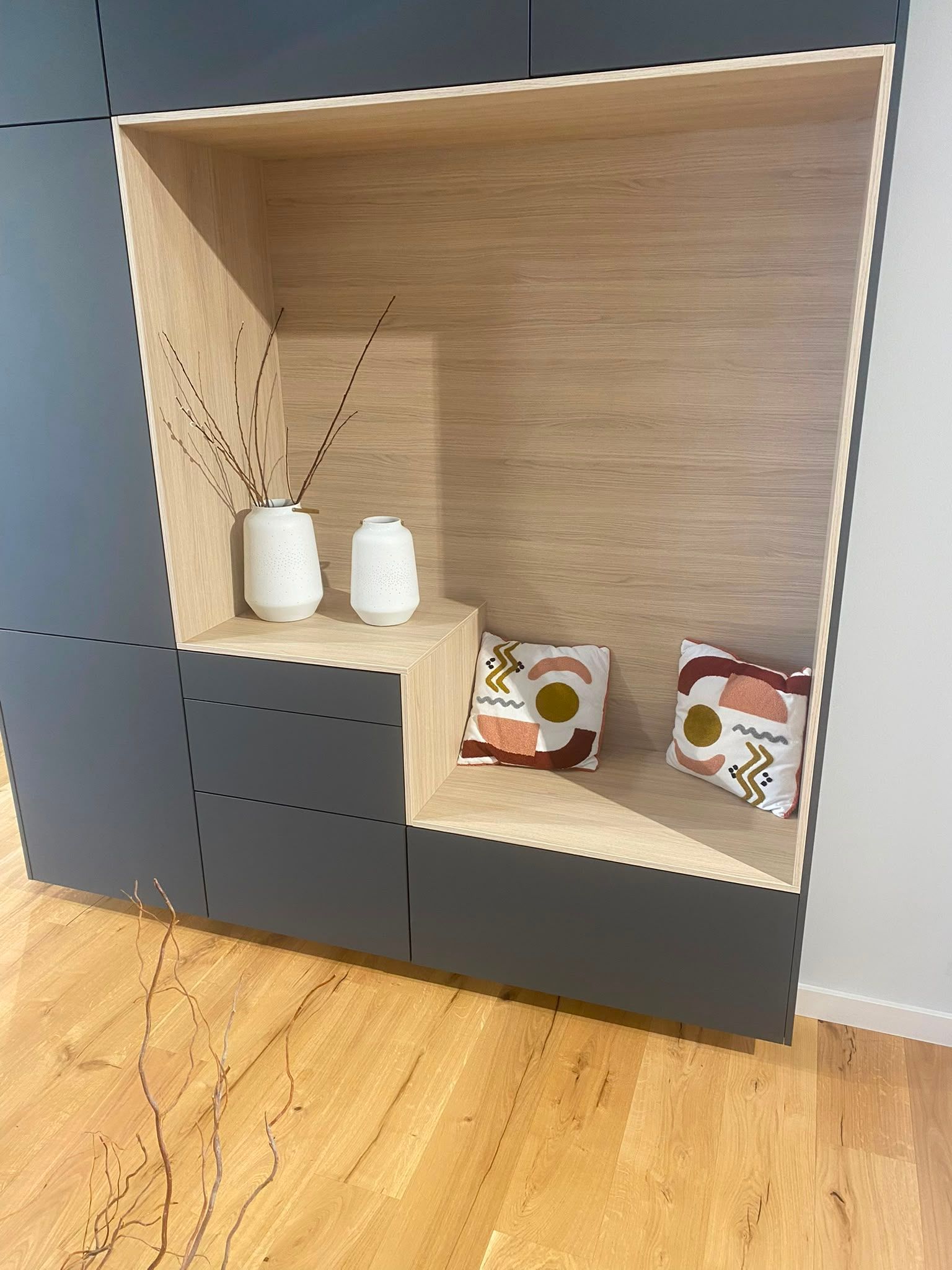 Étagère à casiers ouverte avec intérieur en bois, base gris foncé et quelques petits objets décoratifs à l’intérieur.