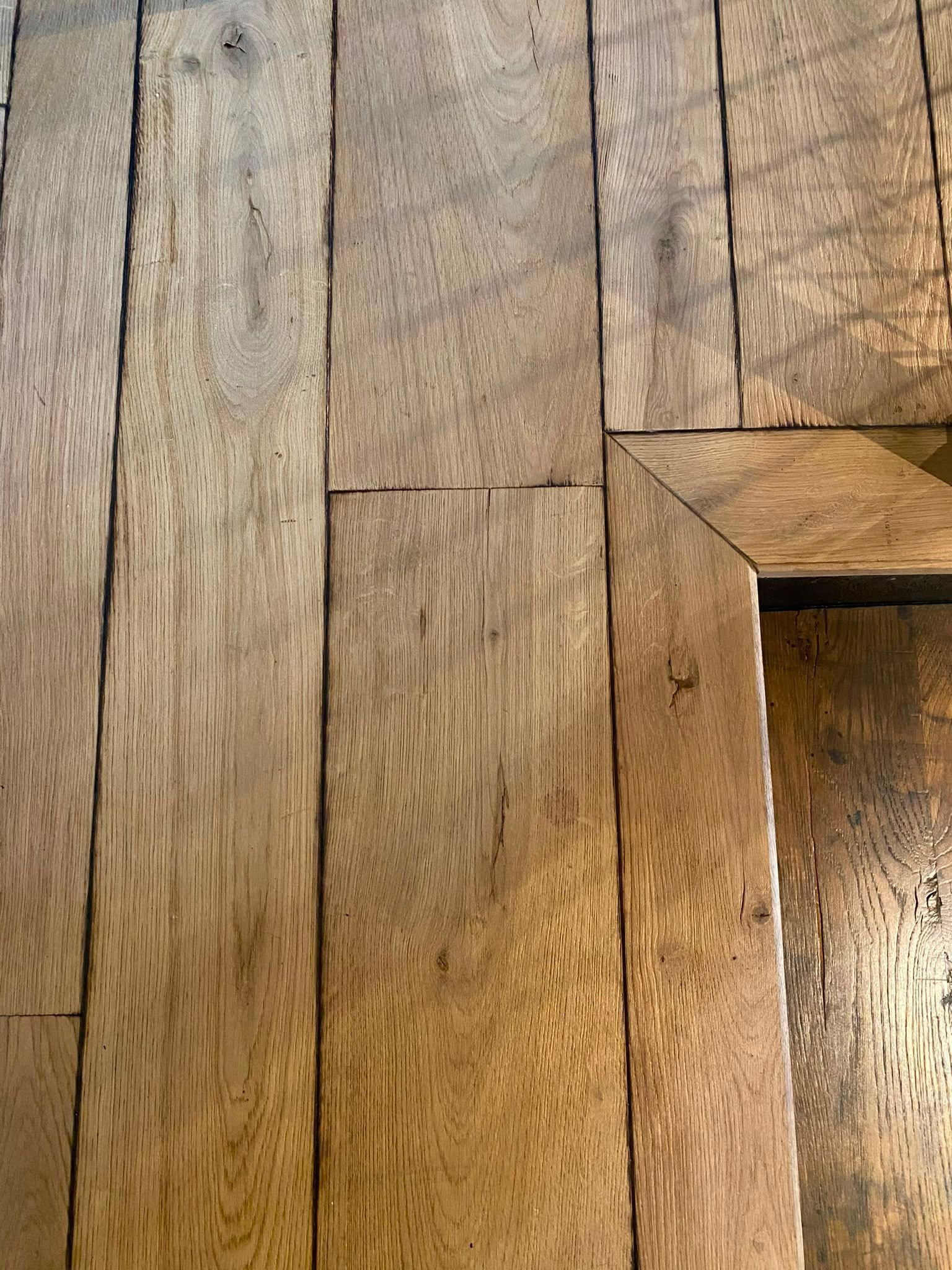 Gros plan sur un plancher en bois patiné, avec une ouverture rectangulaire à droite