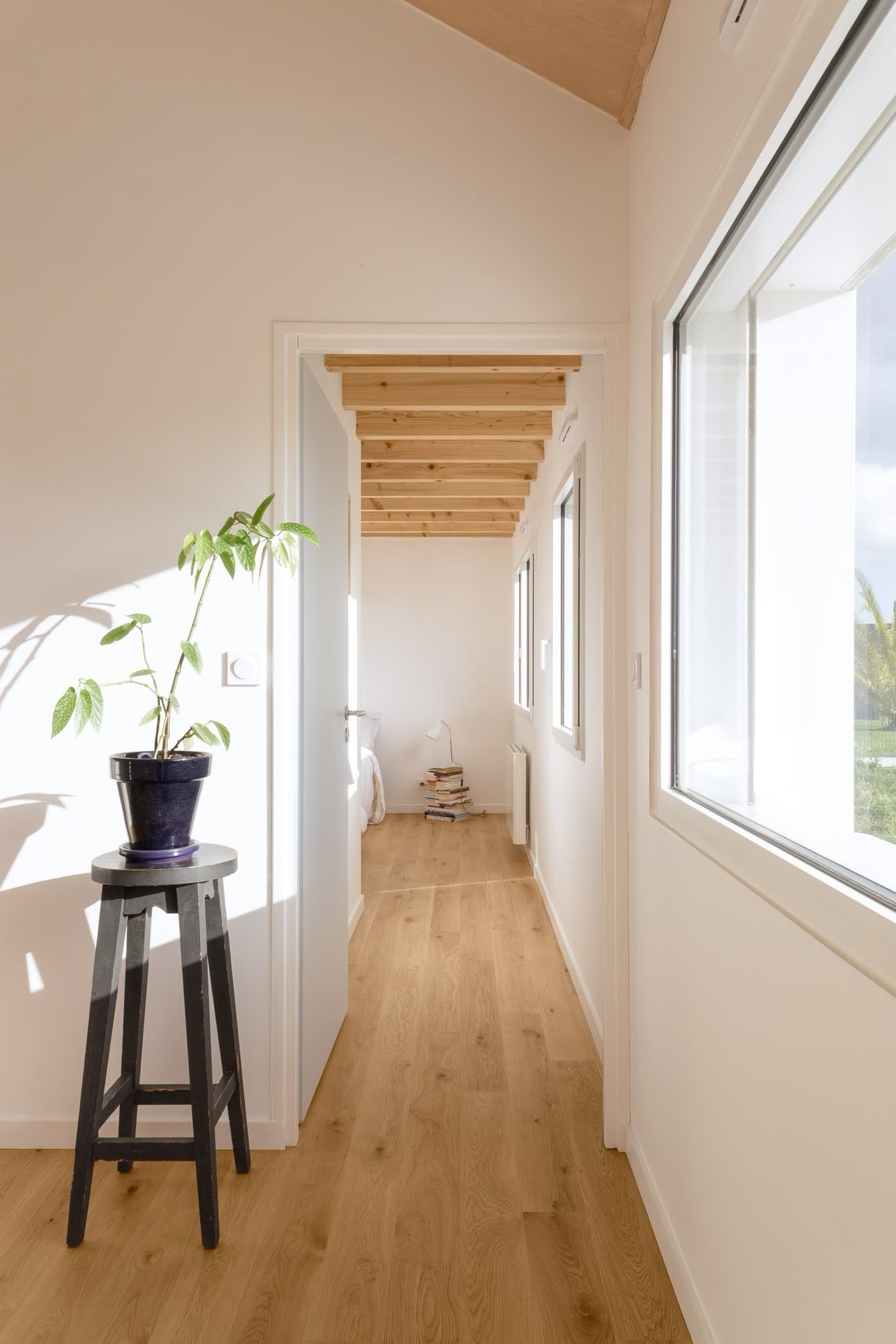 Couloir lumineux avec un parquet, des murs blancs
