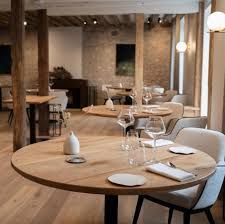 Intérieur de restaurant moderne avec des tables rondes en bois, des chaises beiges et un éclairage d’ambiance chaleureux
