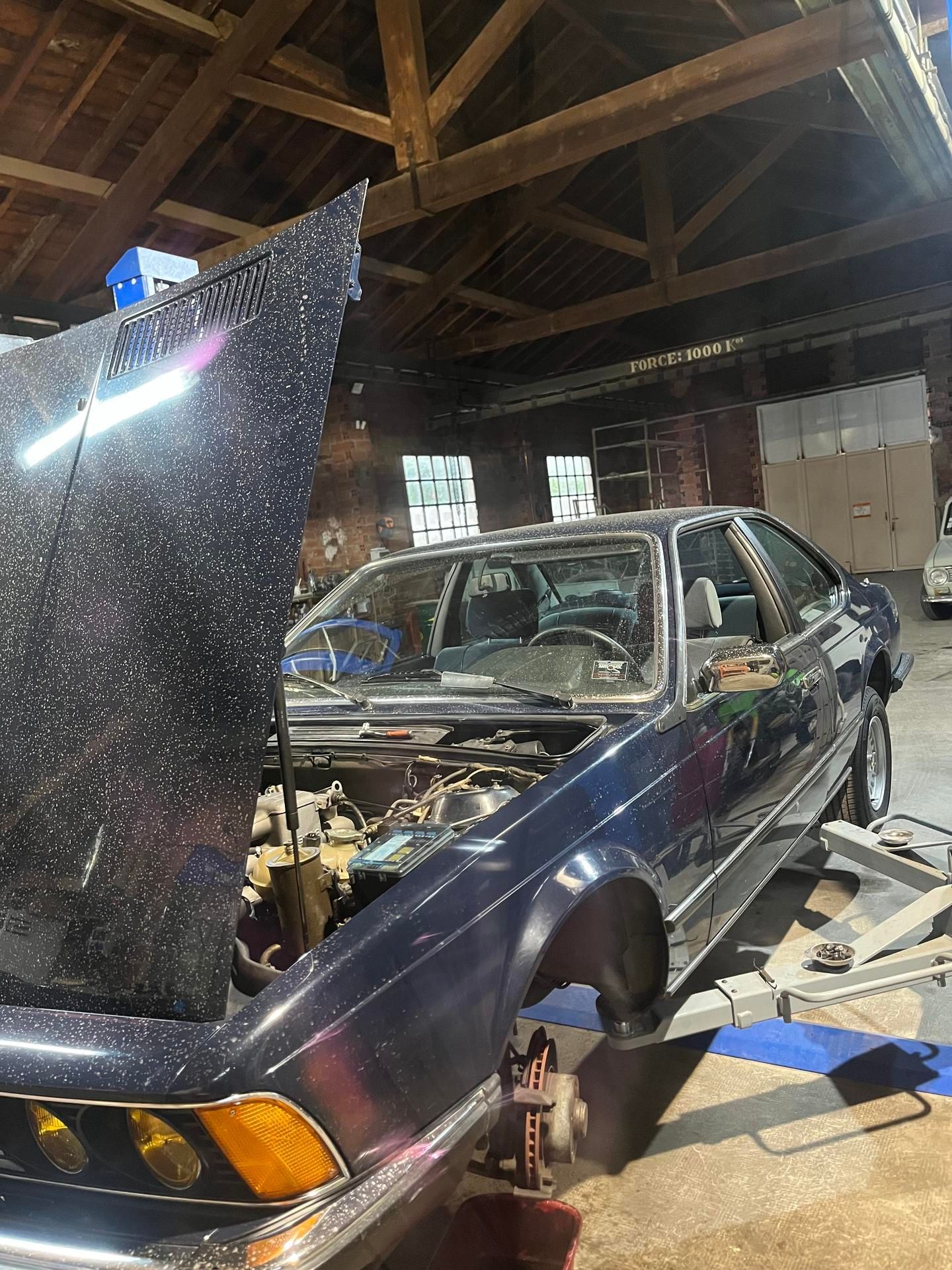 Une vieille berline bleu foncé au capot ouvert