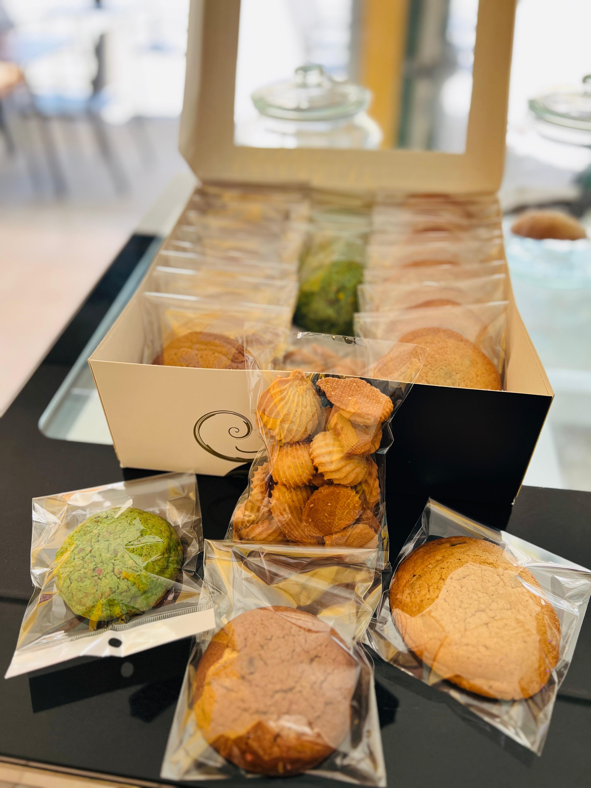 Surtido de pasteles japoneses en una caja de regalo y pequeños dulces envueltos sobre una mesa negra.