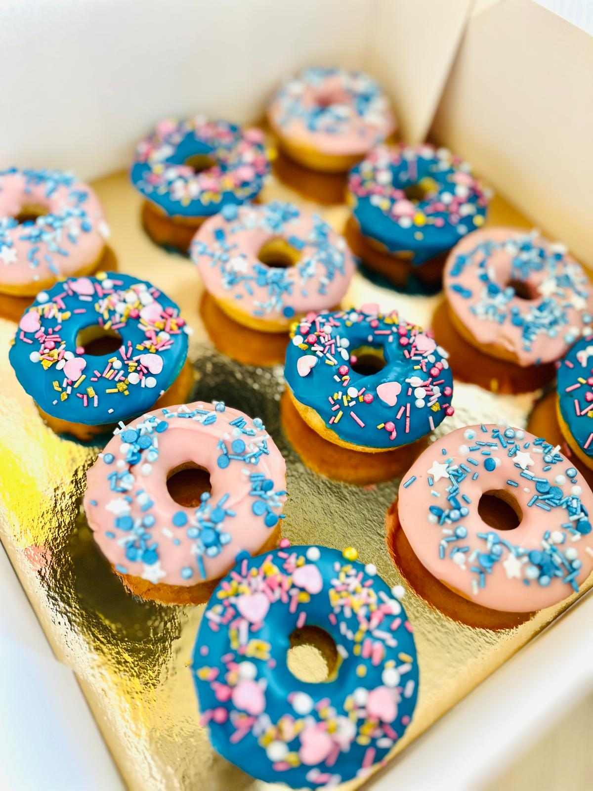 Donas surtidas con glaseado rosa y azul en una caja
