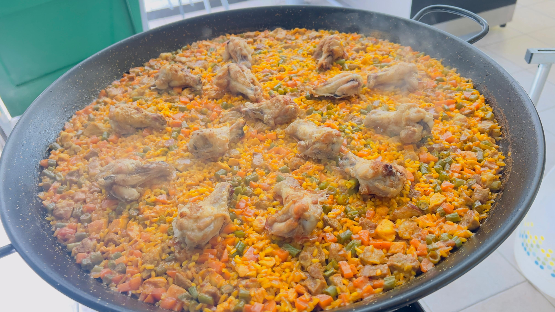 Una olla grande con arroz hirviendo a fuego lento, verduras y trozos de carne, sobre una estufa.