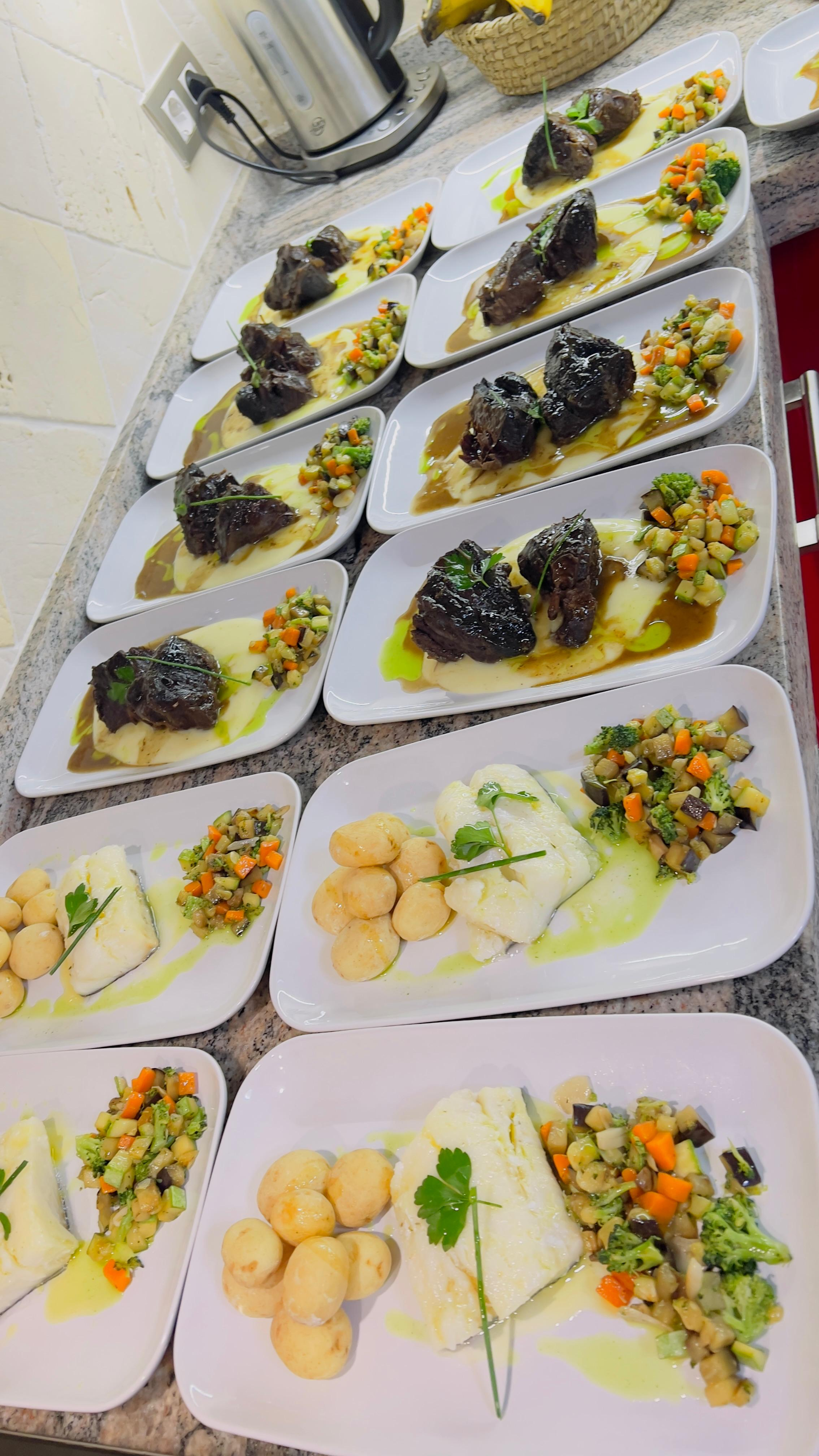 Platos de aperitivos y canapés variados dispuestos sobre una mesa en una cocina de catering.