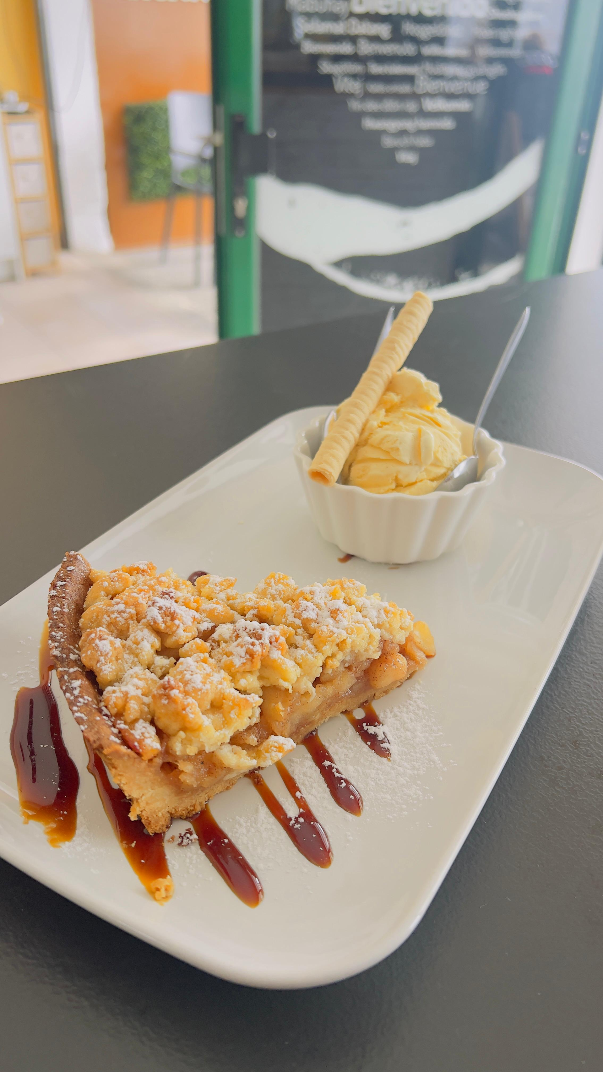 Dos porciones de postre en un plato blanco, una de ellas rociada con salsa de chocolate, junto a una pequeña taza de helado.