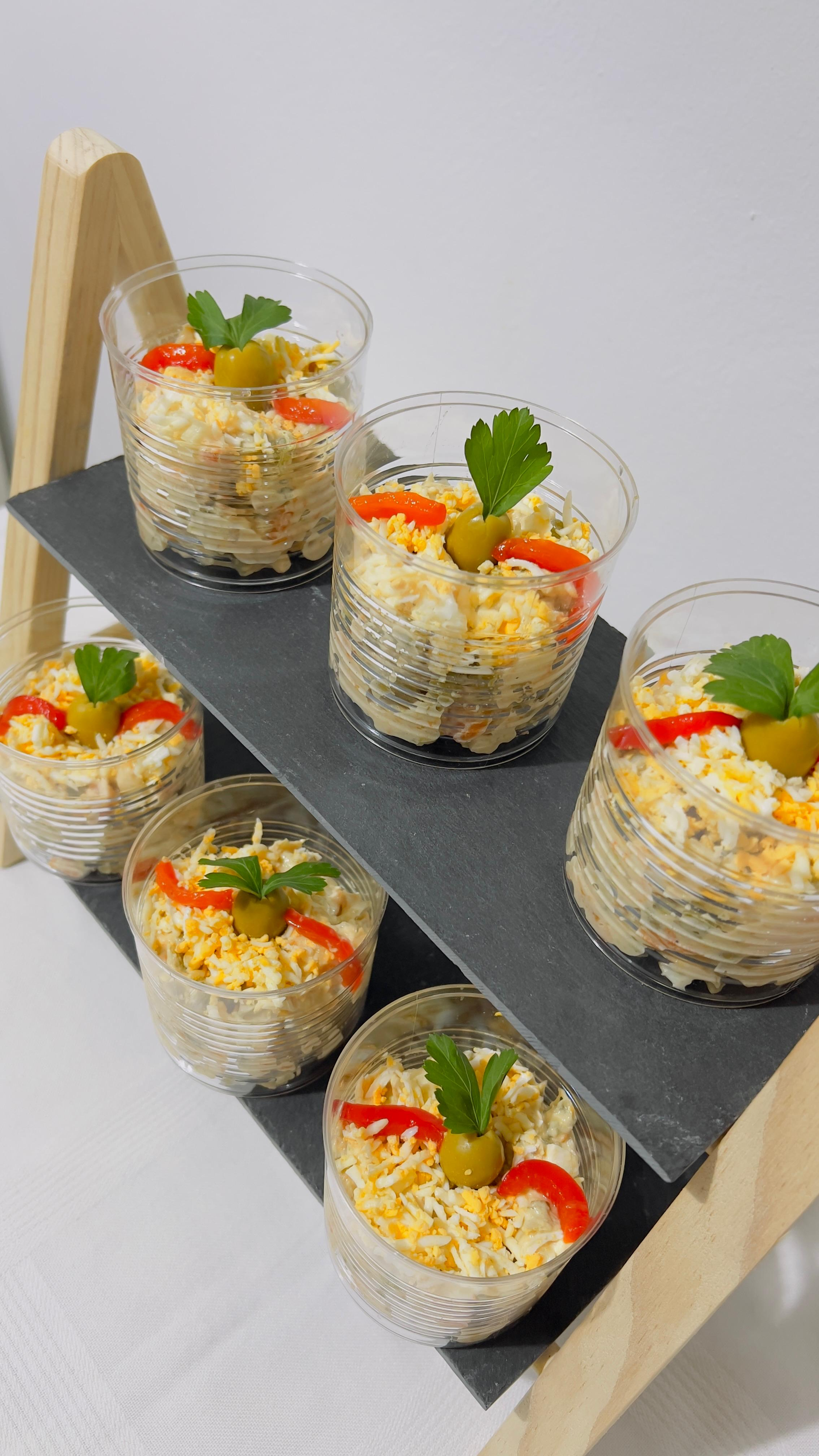 Vasitos de postre pequeños decorados con hojas de menta y fruta sobre una bandeja negra.