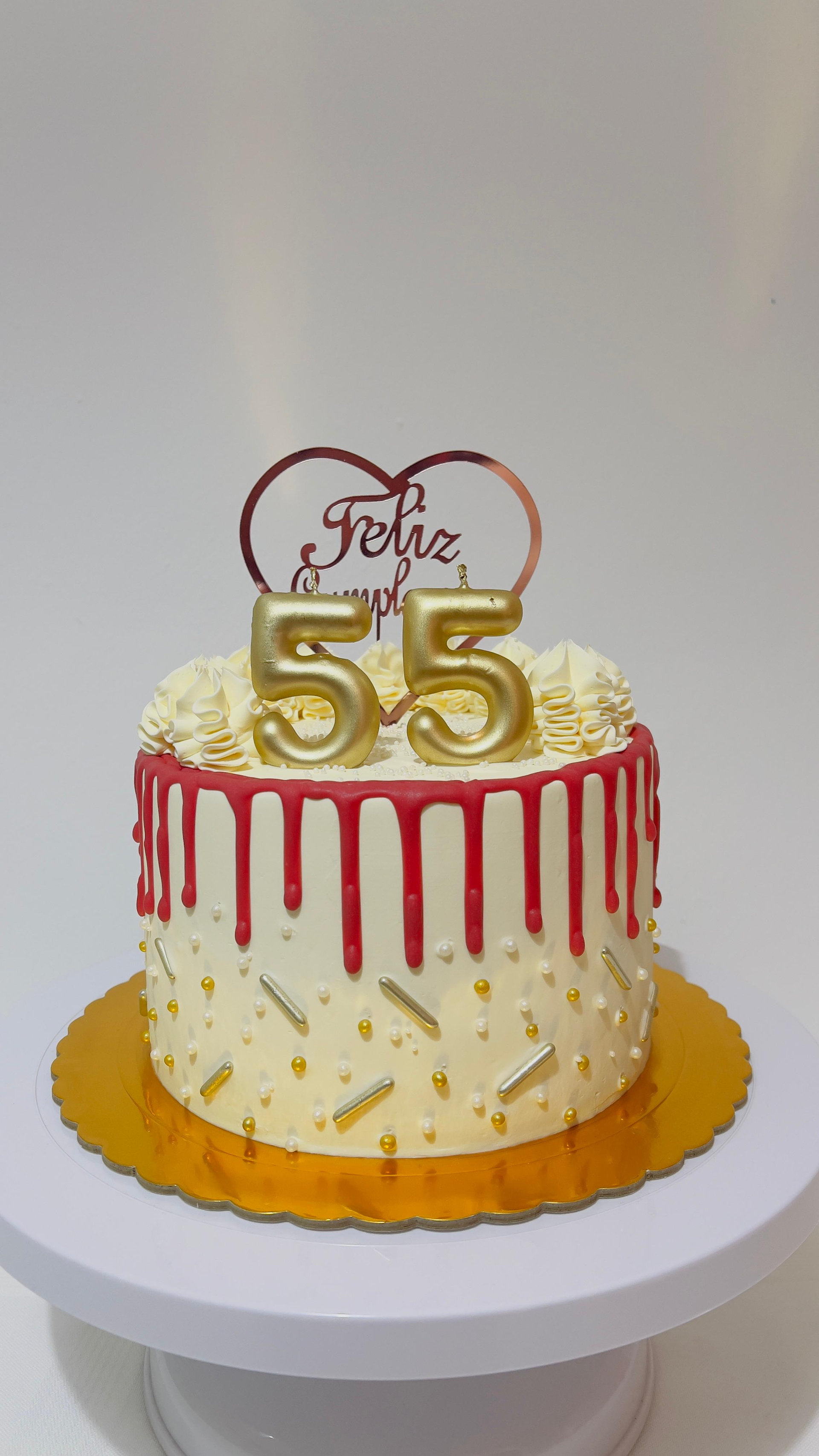 Pastel blanco con glaseado chorreante, adorno dorado con el número 