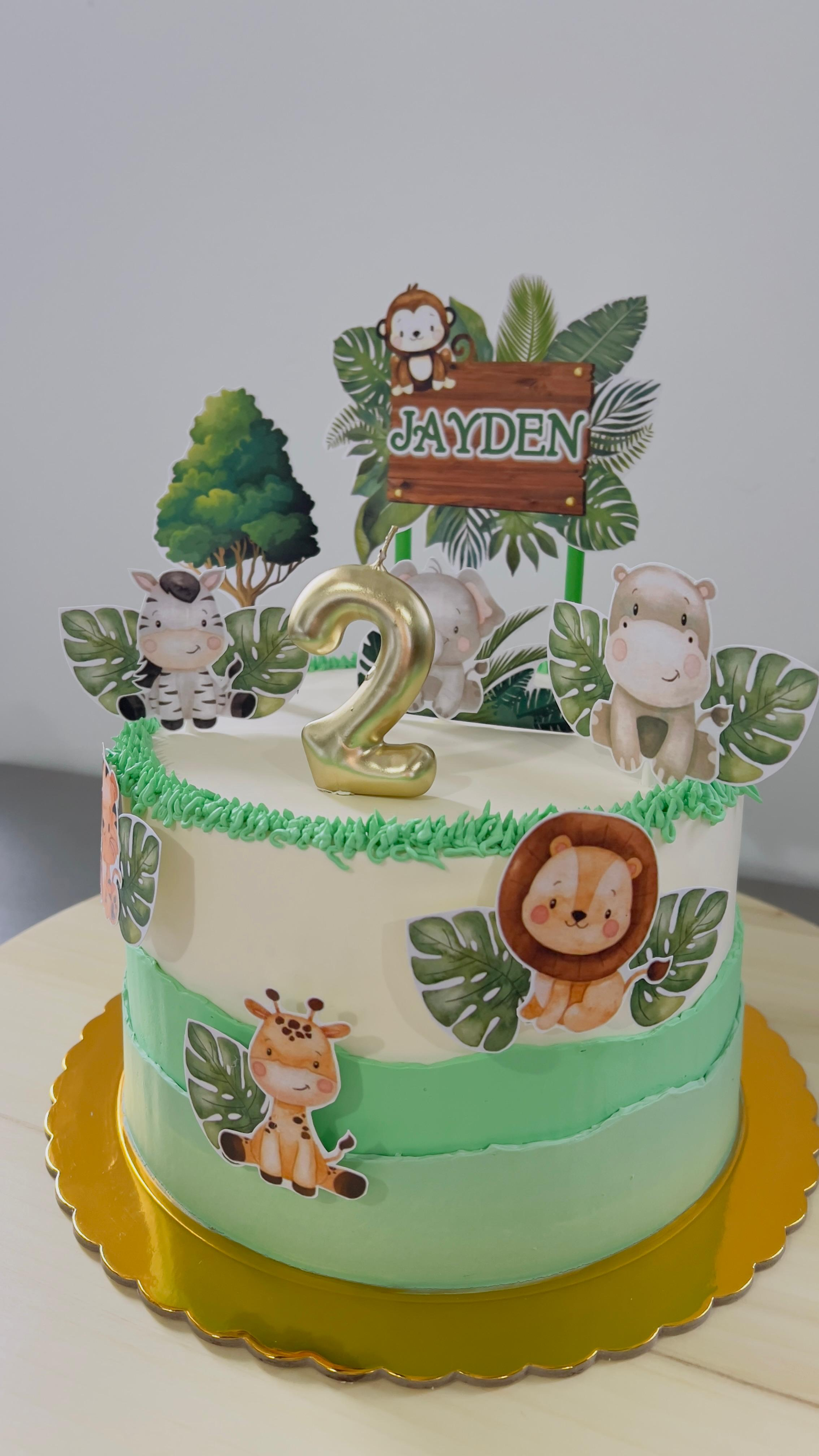 Tarta de cumpleaños decorada en verde menta con adornos de leones y motivos de la selva.