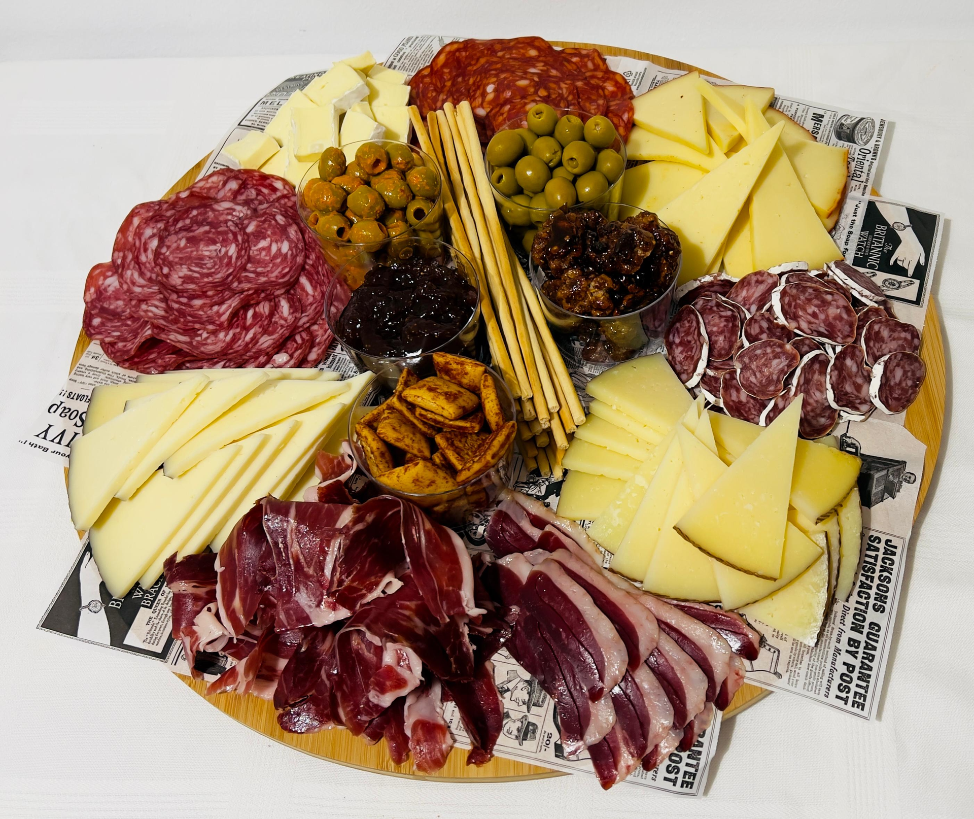 Surtido de quesos, embutidos, aceitunas y patés dispuestos en una tabla de charcutería.