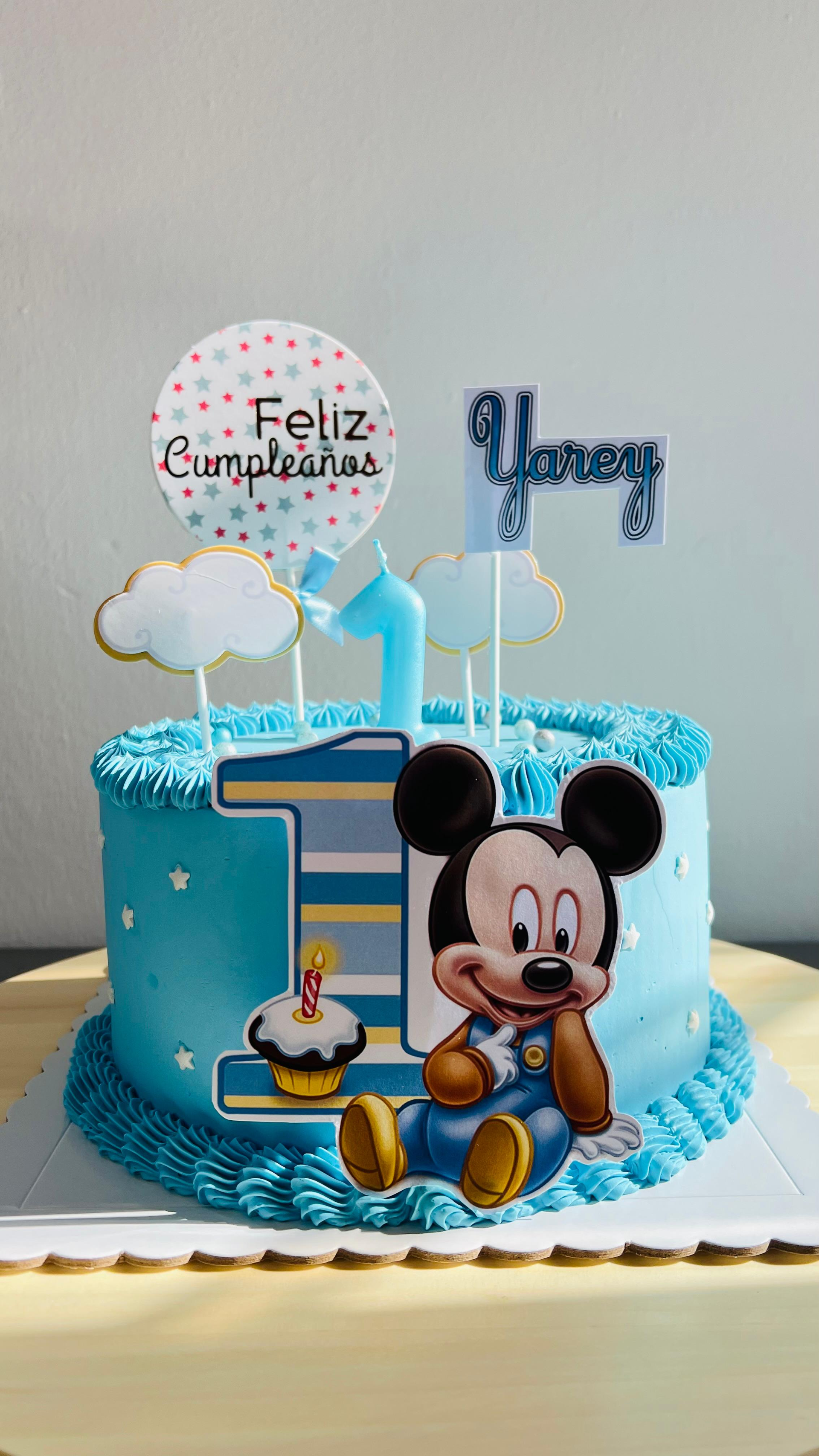 Tarta de cumpleaños de Mickey Mouse con glaseado azul, globos y adorno de “Feliz Cumpleaños”