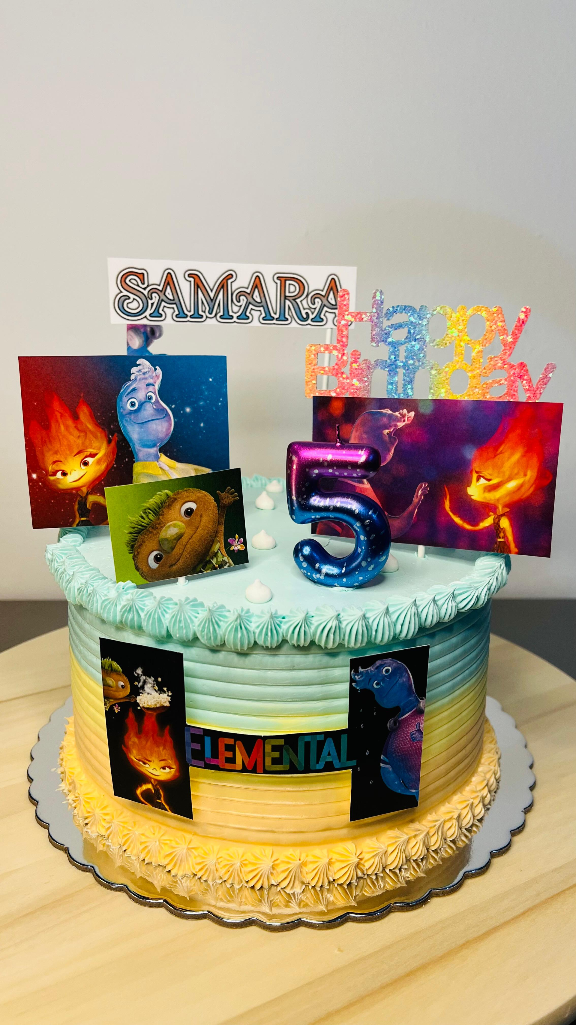 Pastel de cumpleaños decorado con coloridas velas numeradas y adorno de “Jamal” sobre una mesa.