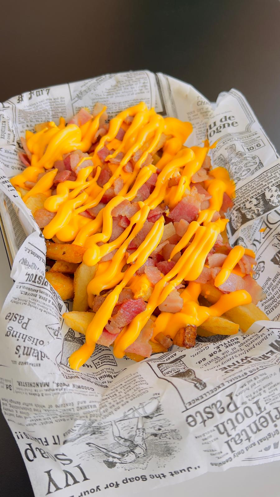 Bandeja de papel con patatas fritas onduladas rociadas con salsa naranja brillante y kétchup.