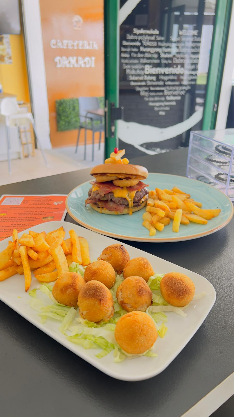 Dos platos de aperitivos fritos y hamburguesas sobre una mesa en un restaurante informal.
