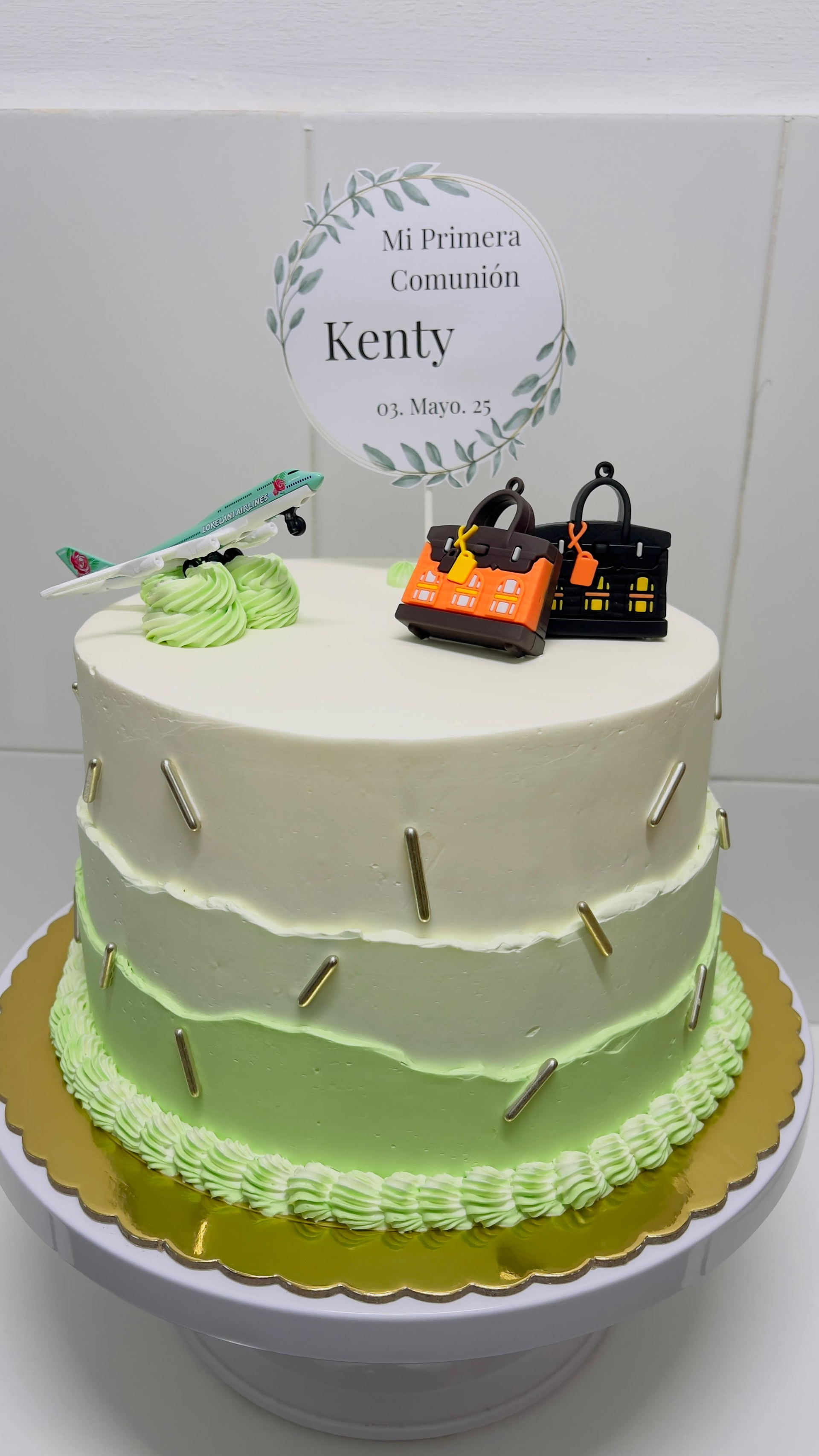 Tarta blanca de dos pisos con borde de glaseado verde, velas naranjas y un adorno que dice 