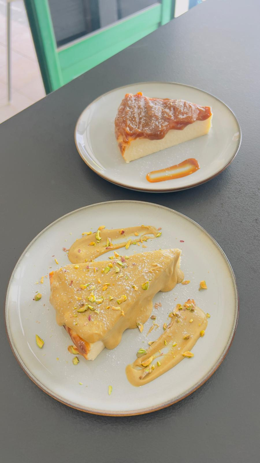 Dos pasteles en platos blancos, uno espolvoreado con azúcar glas y el otro cubierto con crema amarilla.