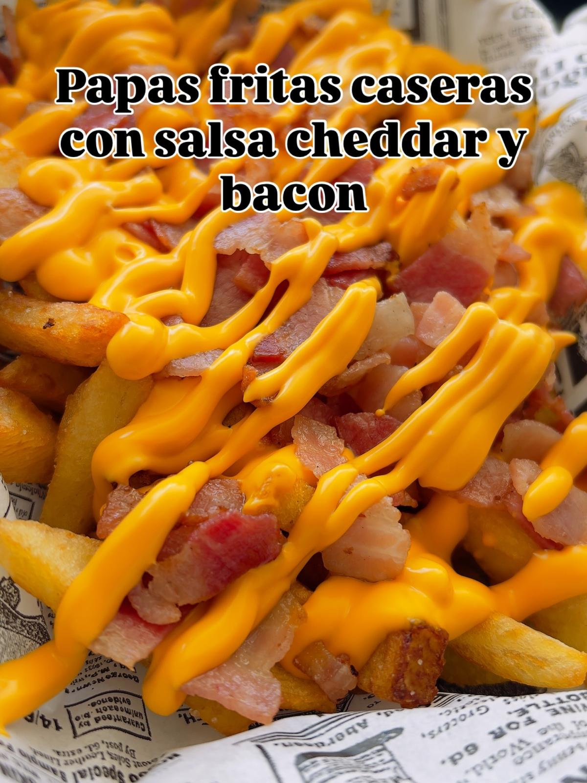 Papas fritas caseras con salsa cheddar y bacon, cubiertas con queso amarillo derretido y trozos de tocino.
