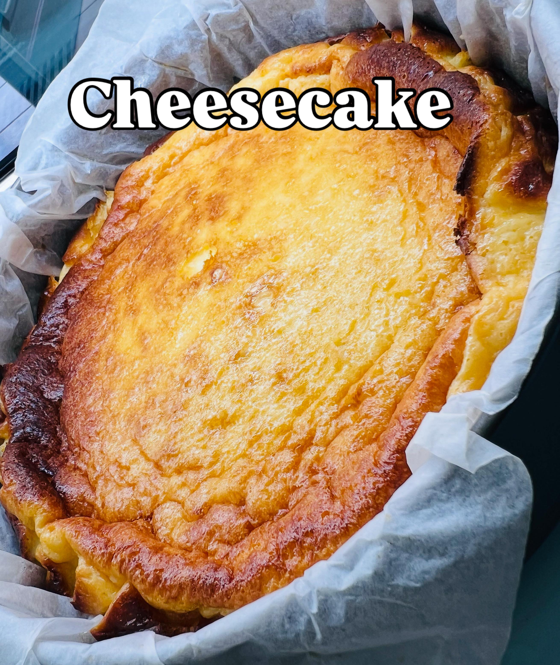 Tarta de queso en un molde forrado con papel pergamino con una capa superior dorada.