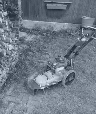 Ein Schwarzweißfoto eines Rasenmähers in einem Garten.