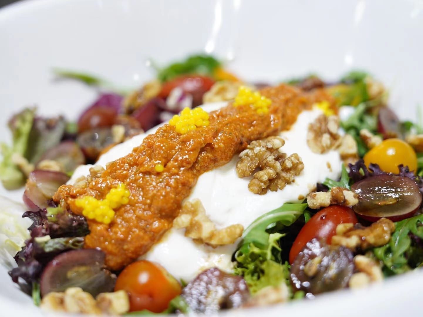 Ensalada con queso burrata, pesto rojo, uvas, nueces y tomates cherry.