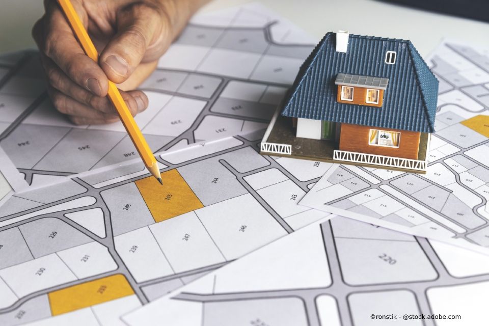 Immobilienplan und Modellhaus auf einem Tisch