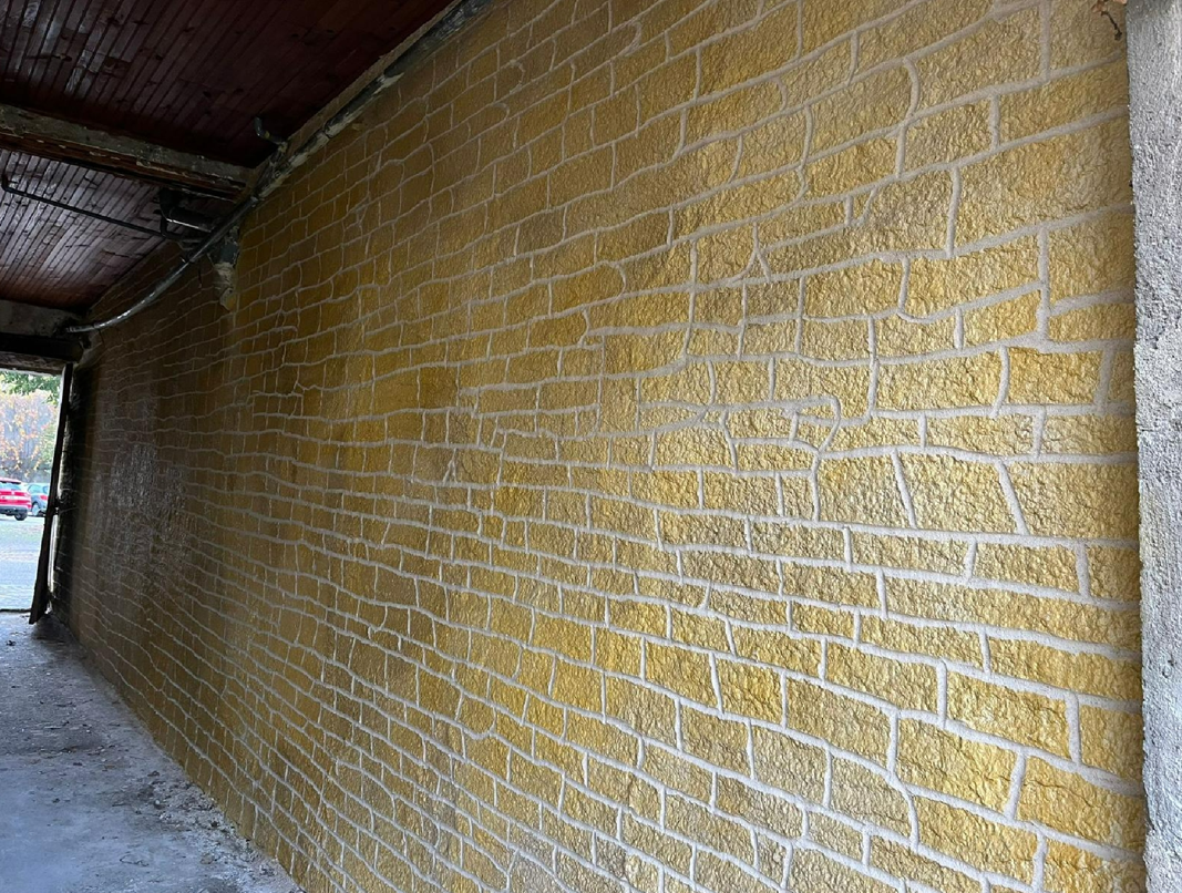 Mur de briques jaunes à l'aspect patiné dans un cadre extérieur.
