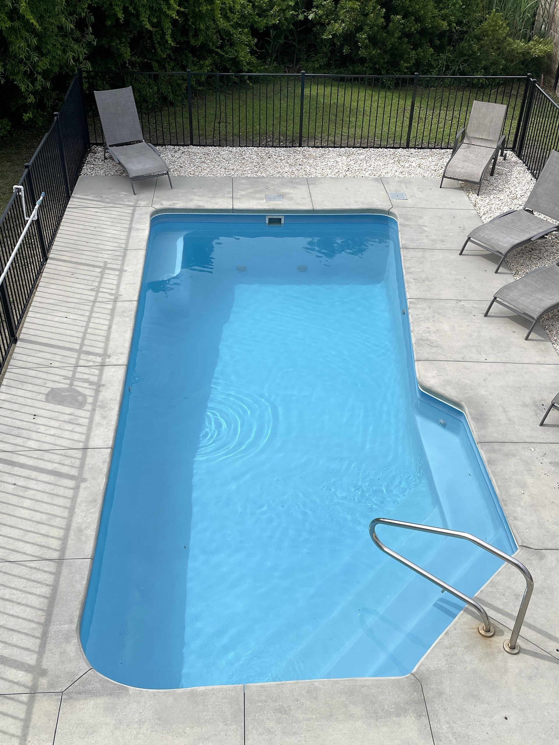 Une piscine en béton avec des transats