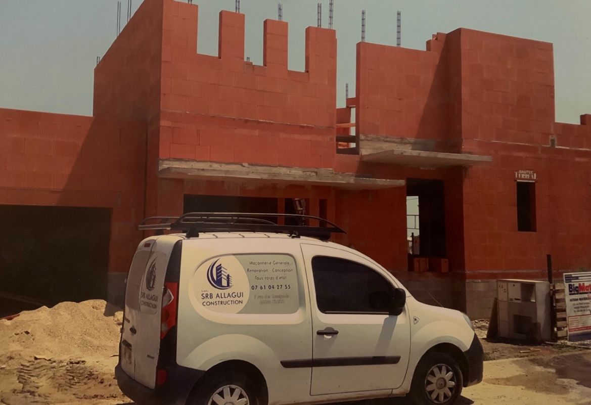 Un véhicule blanc devant une maison en construction