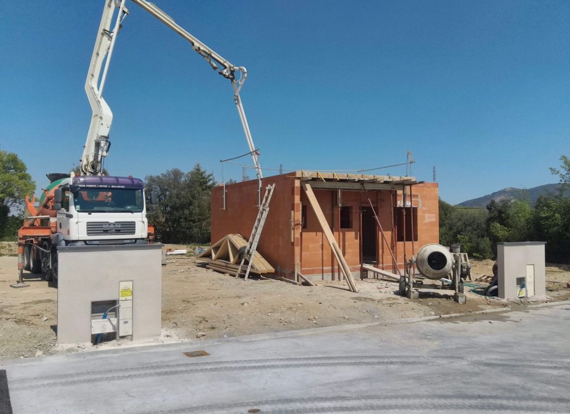 Une maison en construction avec une benne à béton