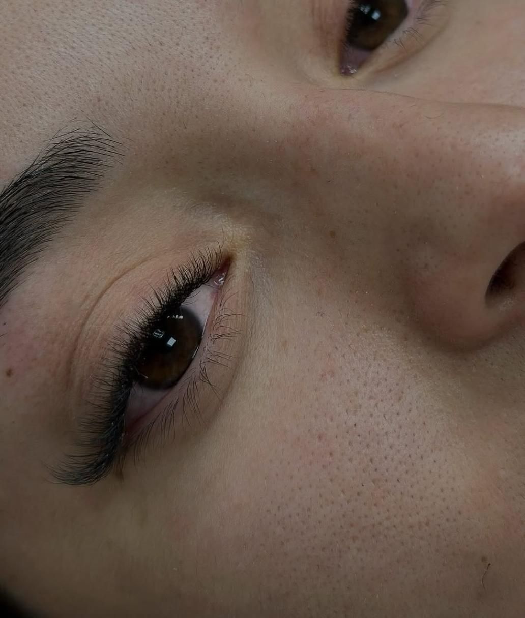 Primer plano del ojo de una persona, mostrando el delineador y los poros visibles. Ojo marrón oscuro, tono de piel neutro.