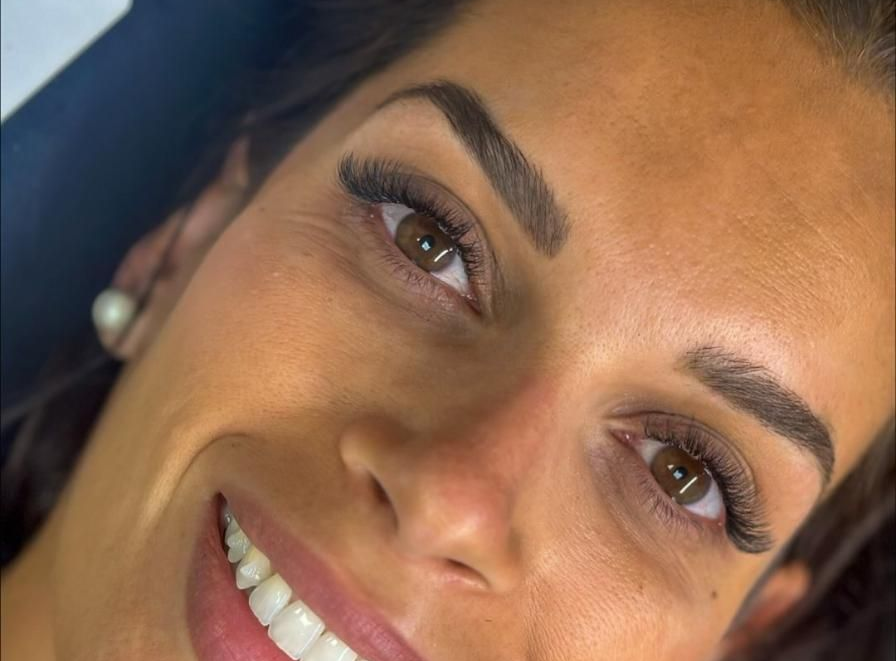 Mujer con cejas oscuras, pestañas, sonriendo, primer plano.