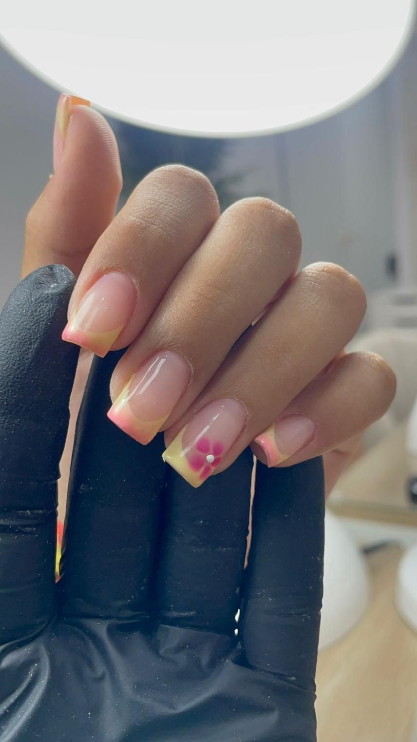 Mano con uñas cuidadas, puntas francesas y diseño floral.