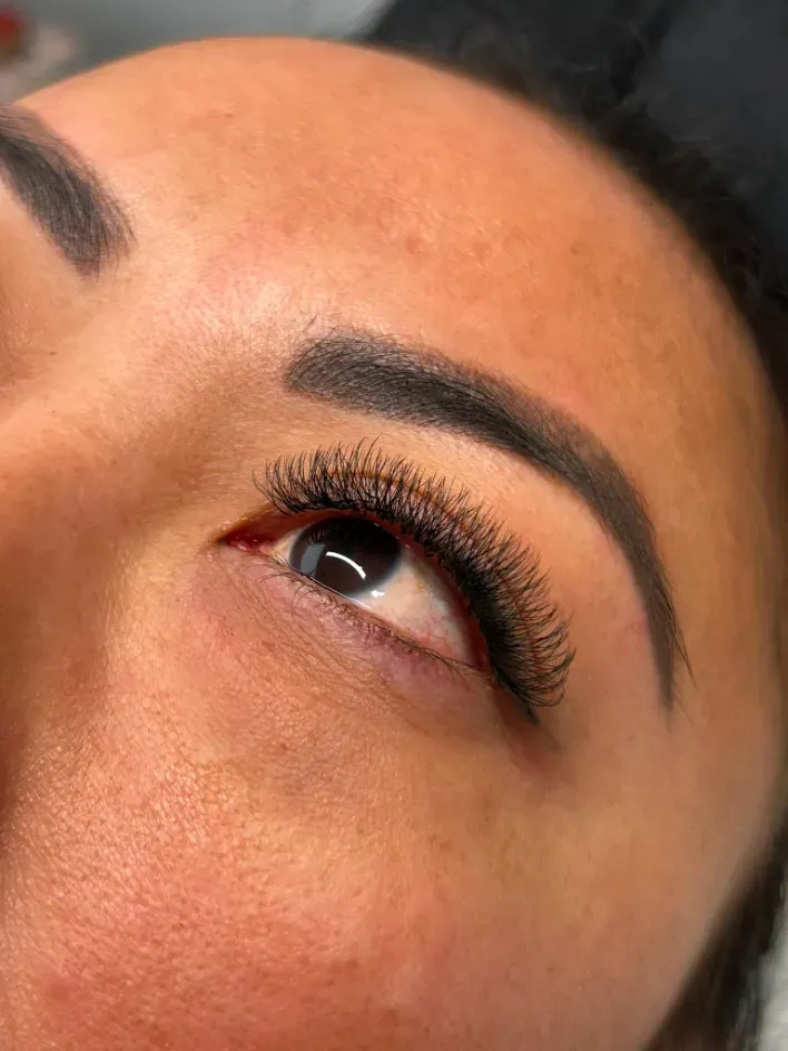 Primer plano del ojo de una persona con largas pestañas y cejas bien definidas, mirando hacia arriba.