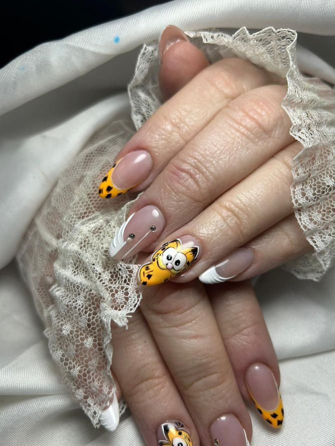 Mano con uñas decoradas con flores amarillas y detalles dorados junto a una pieza decorativa circular dorada.