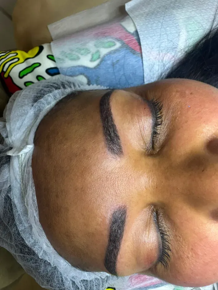 Primer plano del rostro de una mujer con los ojos cerrados, cejas pobladas y una peluca blanca en una peluquería.