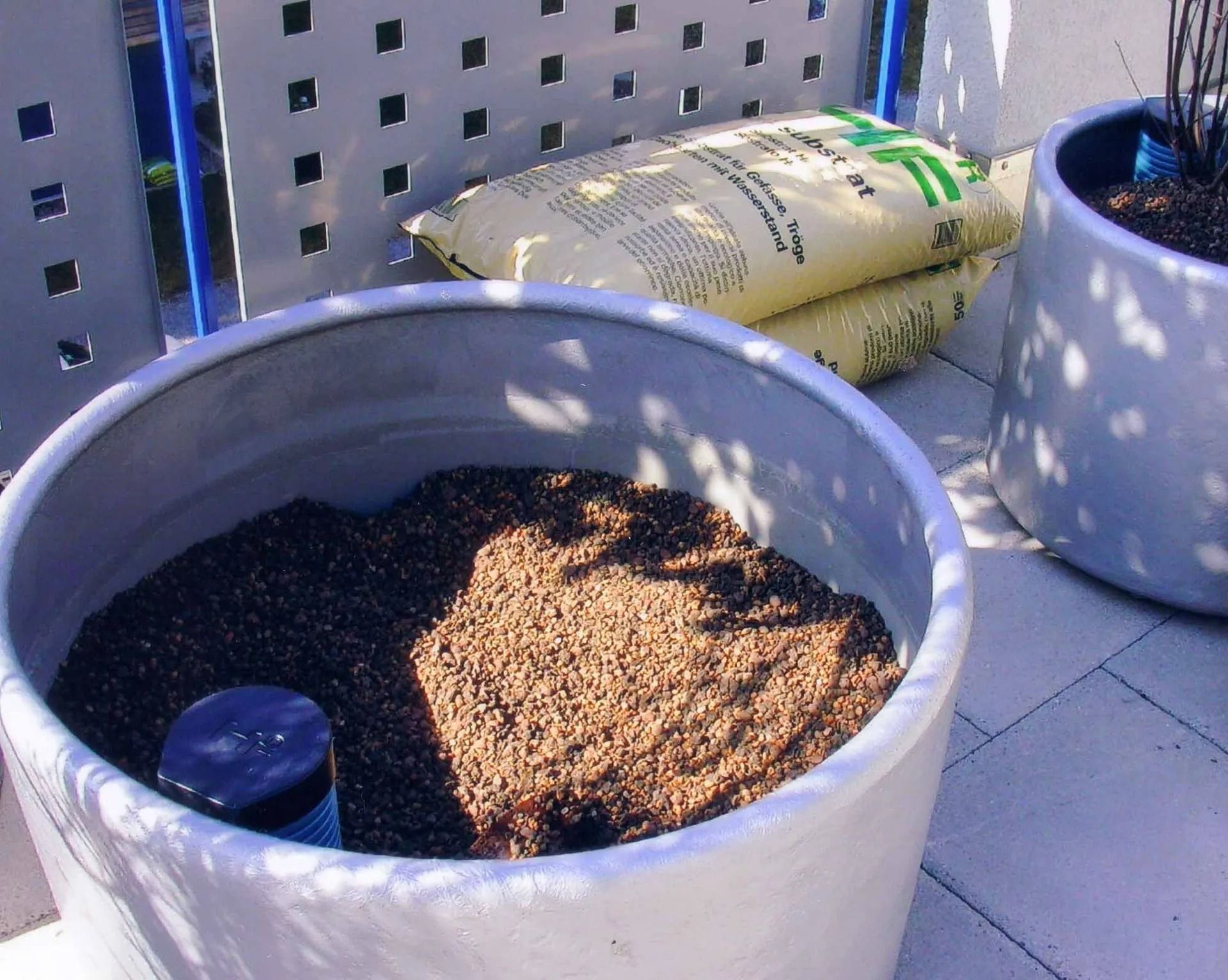 Ein weißer Topf voller Erde und einem blauen Deckel