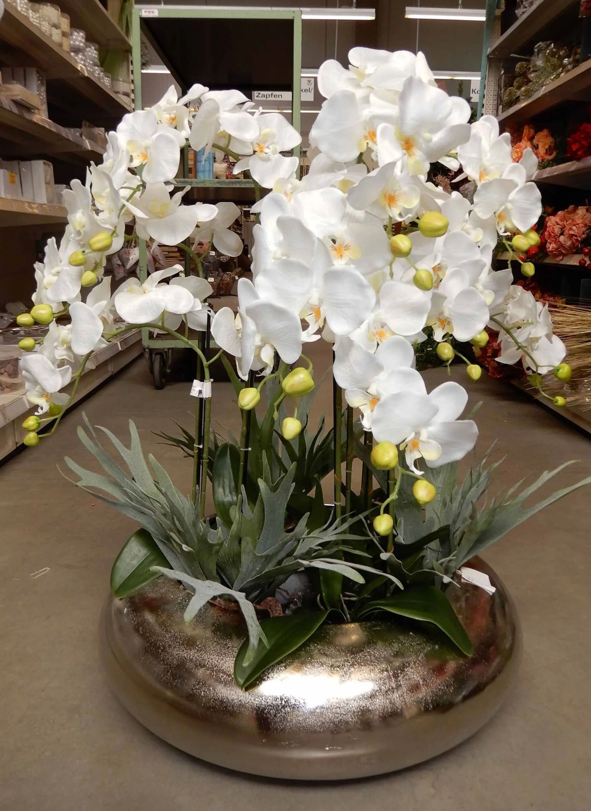 Eine silberne Vase mit weißen Blumen in einem Geschäft