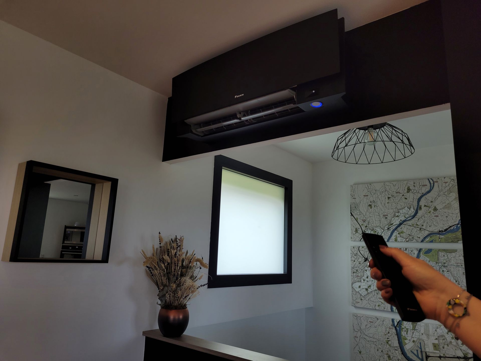 Climatiseur noir et une main de femme tenant une télécommande