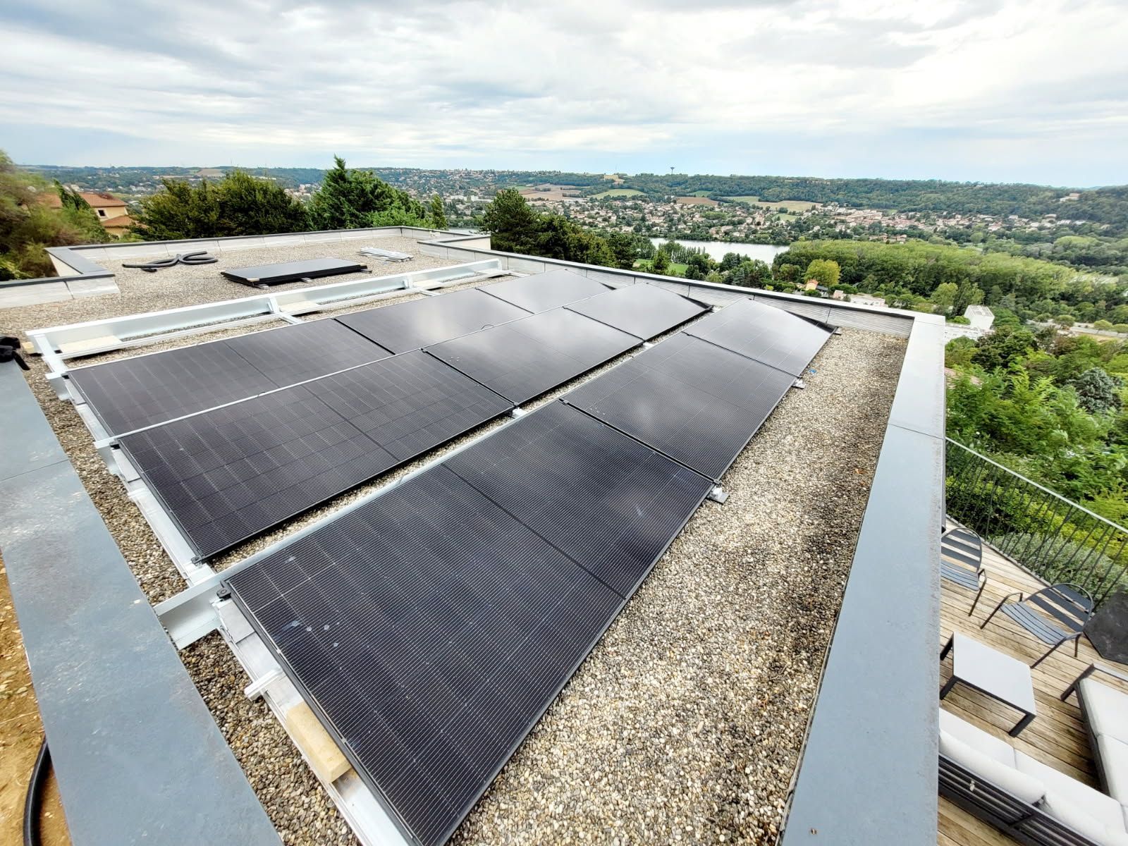 Panneaux solaires installés sur un toit plat donnant sur un paysage pittoresque et verdoyant.