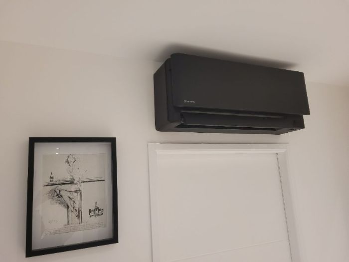 Climatisation STYLISH noir au dessus d'une porte blanche