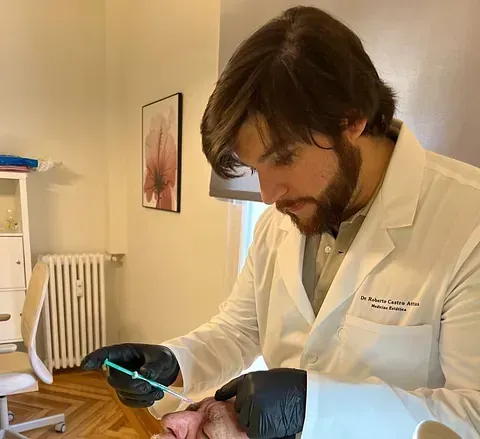 Un hombre con una bata de laboratorio sostiene una aguja en su mano.