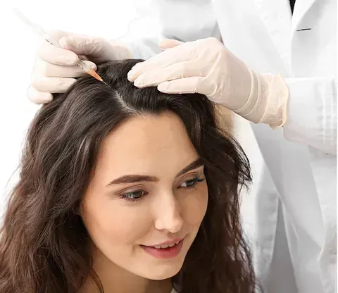 Una mujer recibe una inyección en el cabello por parte de un médico.