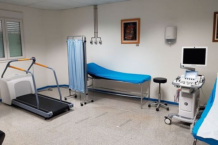Un consultorio médico con una cinta de correr y una máquina de ultrasonido