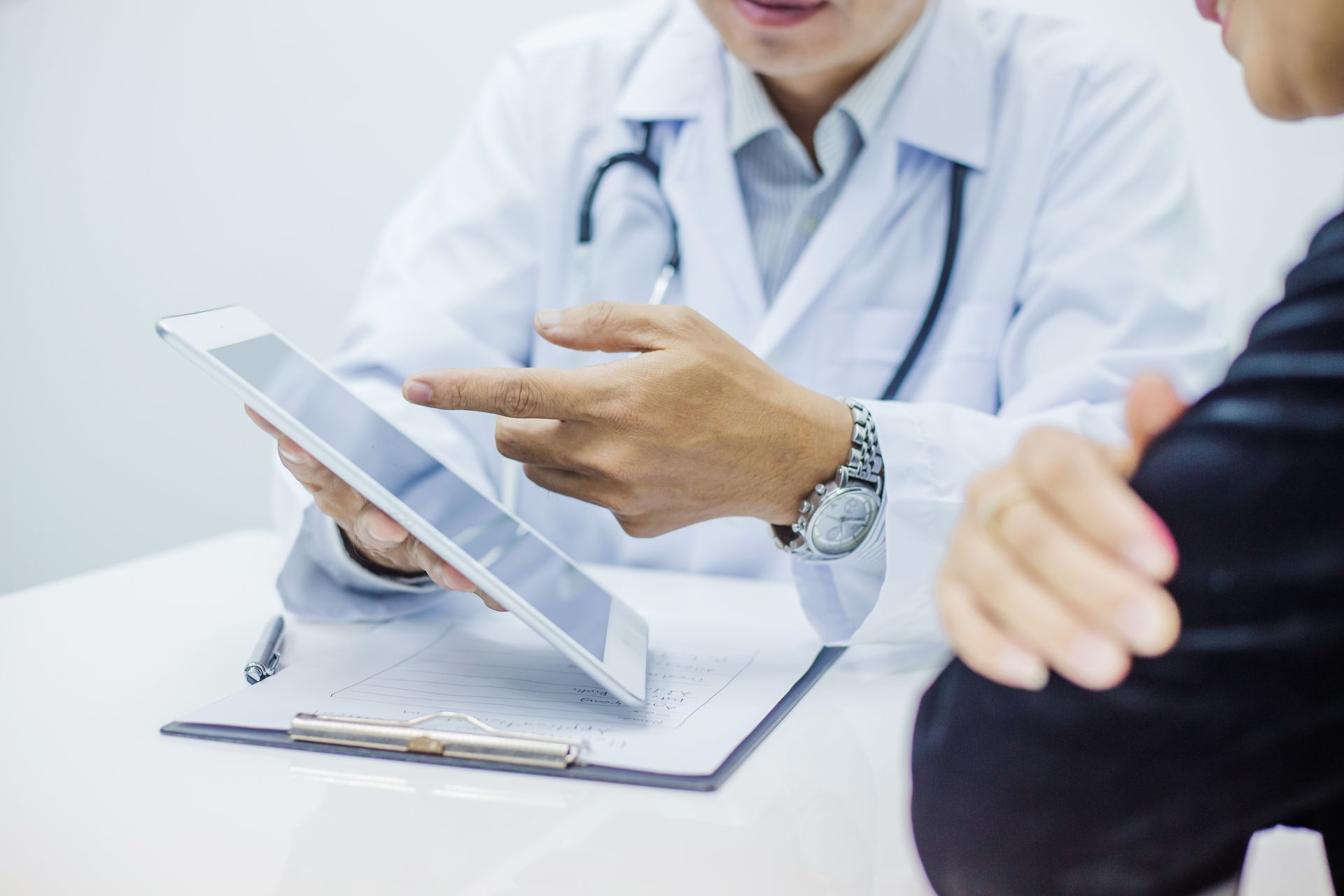 ein Arzt zeigt einem Patient etwas auf einem Tablet