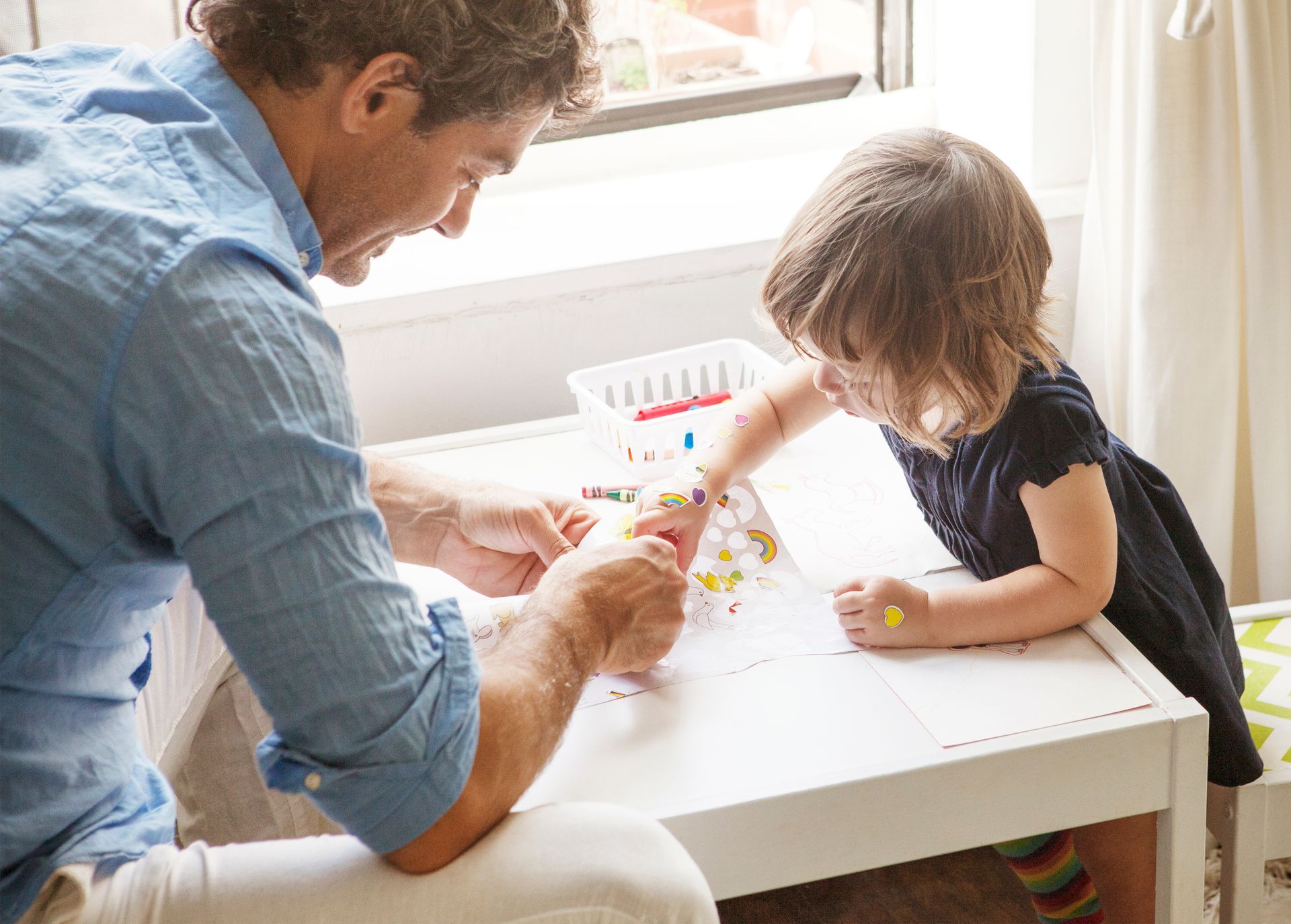 ein Mann und ein kleines Mädchen sitzen an einem Tisch und malen mit Kreide