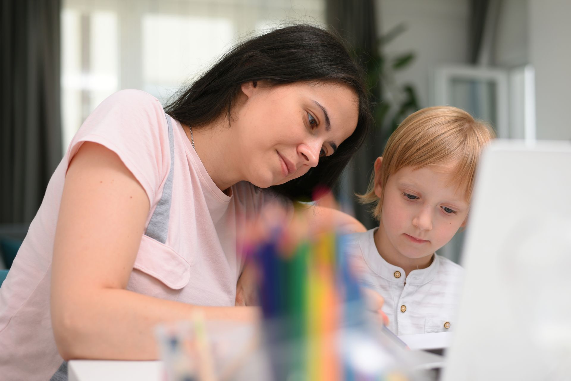 Eine Frau hilft einem kleinen Jungen beim Schreiben