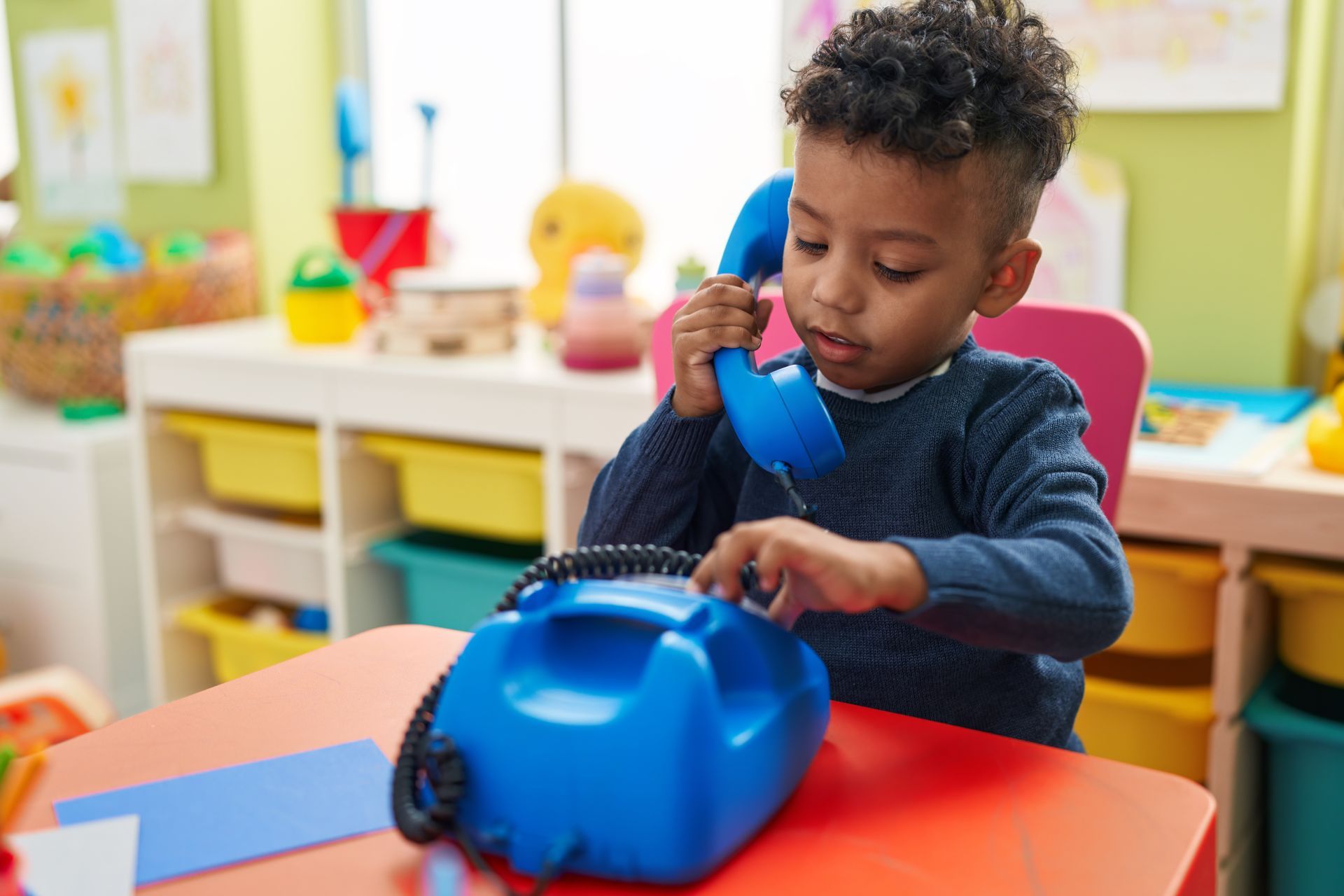 ein kleiner Junge spielt mit einem blauen Telefon