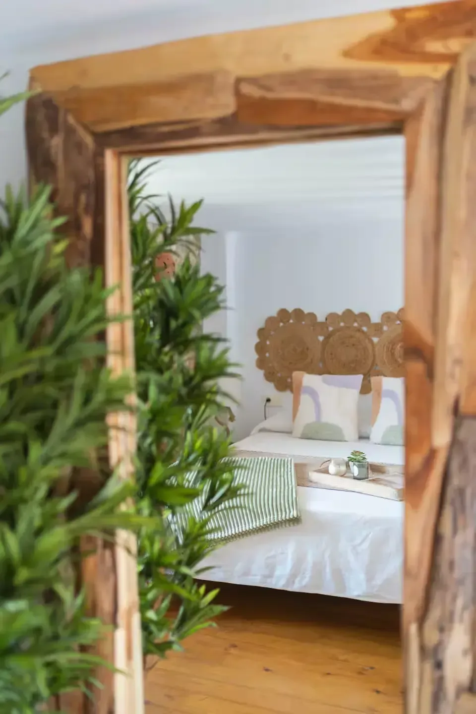 Un marco de madera rústica da paso a un acogedor dormitorio con cabecero tallado, ropa de cama blanca
