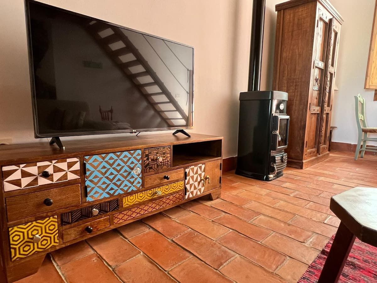 Un televisor de pantalla plana está colocado encima de un centro de entretenimiento de madera en una sala de estar.